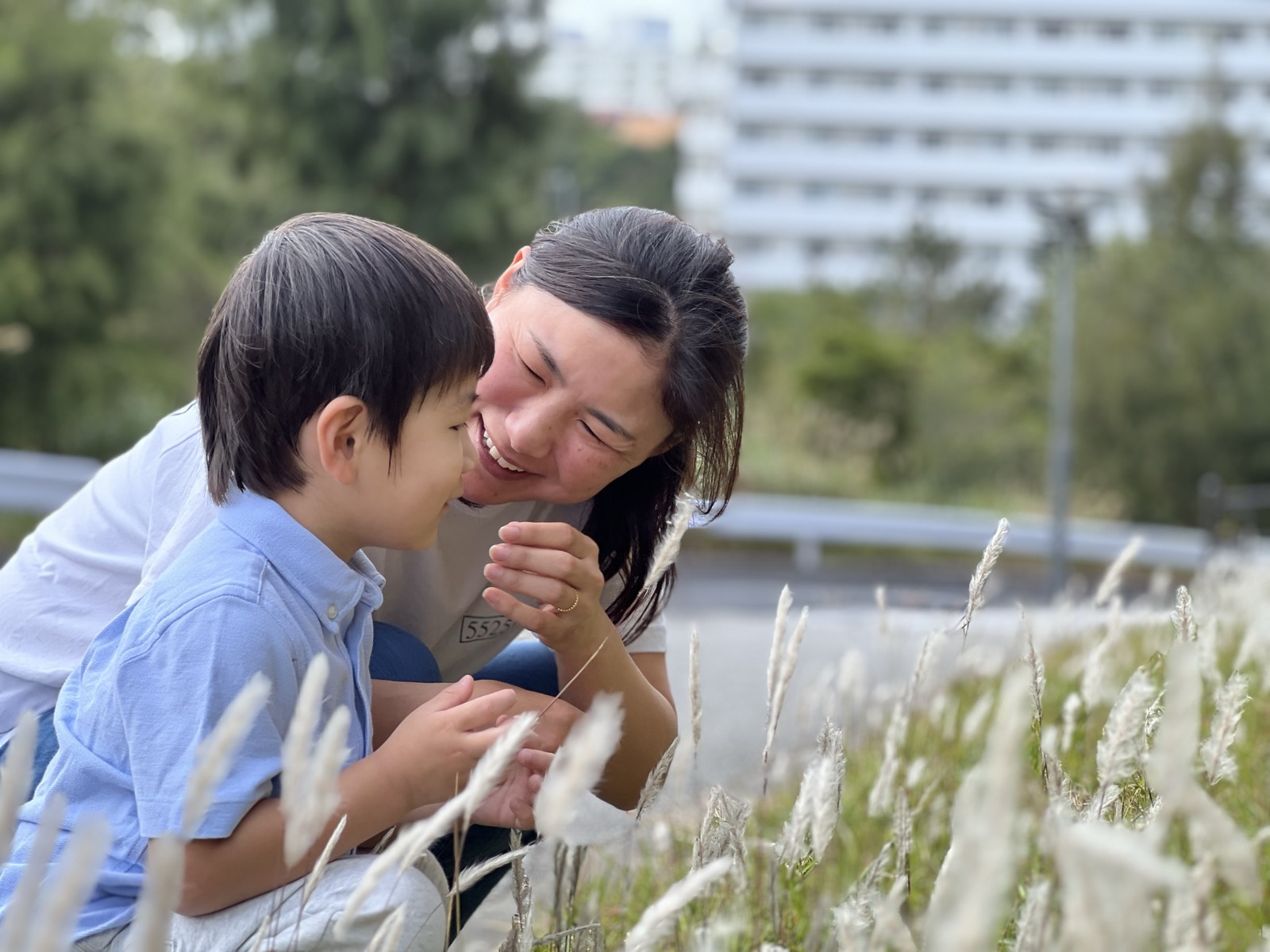 草の生えた土手で子どもと顔を寄せて笑う横峯さくら